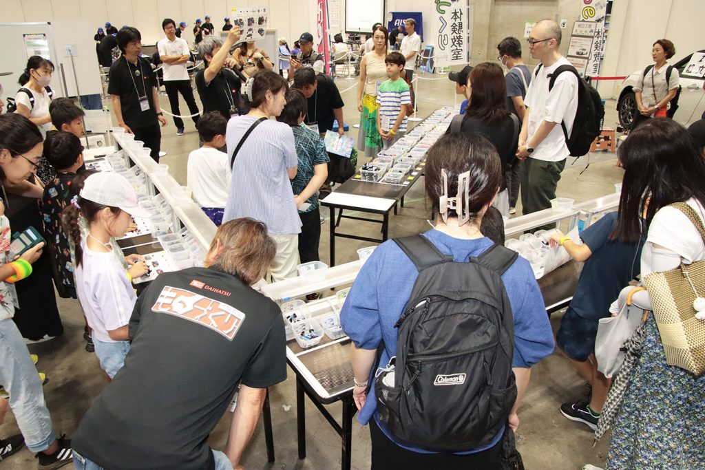 車両組立ラインを模した流れ作業の様子。写真中央奥が部品庫、手前左右が組立ライン